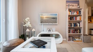 Una sala moderna con televisor de pantalla plana, una estantería, una mesa de centro y un área de descanso confortable.