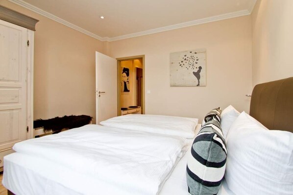A hotel room with two beds, a wardrobe, a mirror, and a wall art piece.