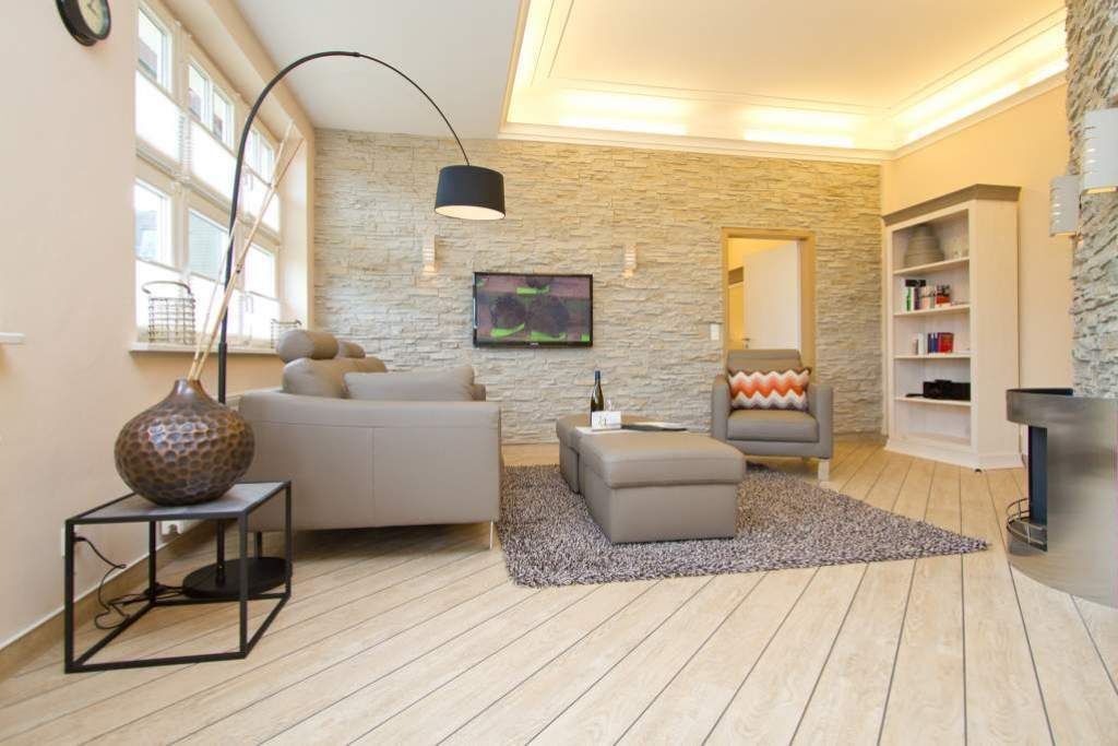 Un salon moderne avec un mur en pierre, un canapé, une table basse, une lampe et une cheminée.