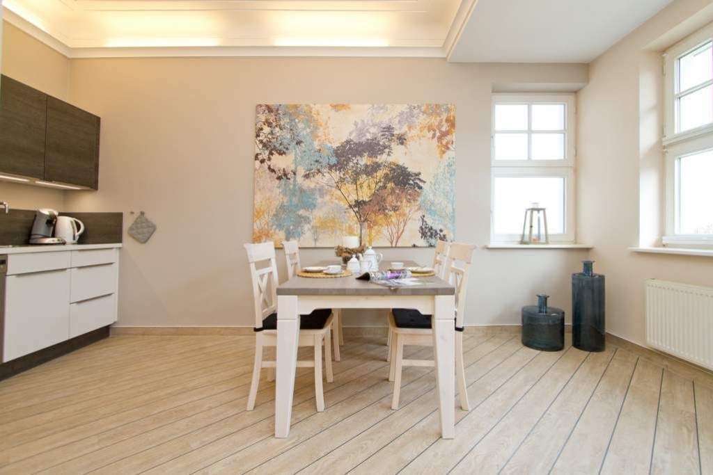 Een moderne keuken met een eettafel voor vier personen, een groot abstract schilderij aan de muur, en een raam dat natuurlijk licht binnenlaat.