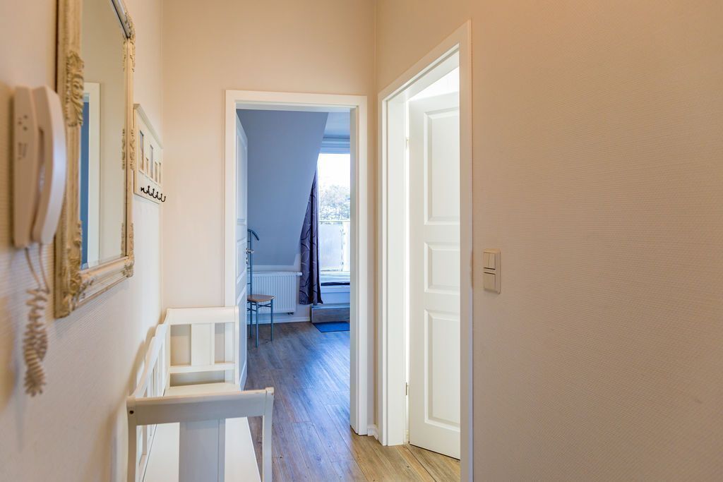 A hallway with a white door, a white bench, and a radiator.