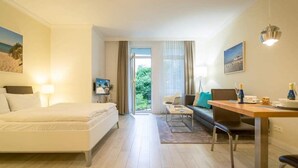 Een moderne hotelkamer met een bed, een bureau, een stoel en uitzicht op het omliggende landschap.
