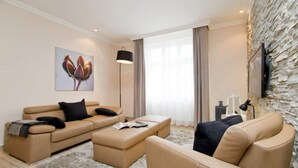 Ein modernes Wohnzimmer mit einer beigefarbenen Sofagarnitur, einem Couchtisch und einem an einer Steinwand montierten Fernseher.