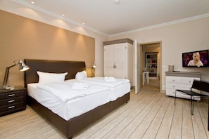 Ein Hotelzimmer mit einem großen Bett, Nachttischlampen, einem Fernseher, einem Schreibtisch und einem Kleiderschrank.