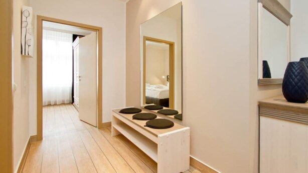 Ein Flur mit einer hölzernen Bank, einem Spiegel und einer Tür zu einem Zimmer.