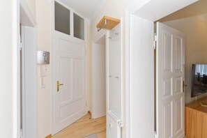 Um corredor com portas brancas, um armário de madeira e um termostato na parede.