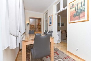 Ein Essbereich mit einem Holztisch, Stühlen, einer Glasschrank und einem Gemälde an der Wand.