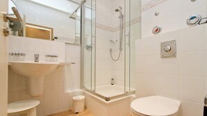 A modern bathroom with a glass-enclosed shower, a white sink, and a toilet.
