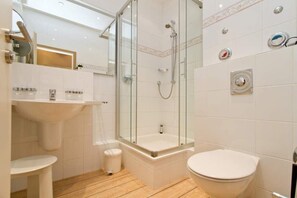 Un baño moderno con ducha de vidrio, lavamanos blanco y retrete.