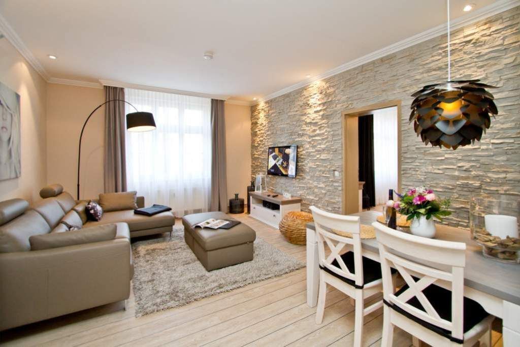 Ein modernes Wohnzimmer mit Sofa, Hocker und Essbereich mit Stühlen.