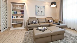 A modern living room with a sectional sofa, a small ottoman, a bookshelf, and a floor lamp.