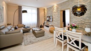 A modern living room with a sofa, ottoman, and dining area with chairs.