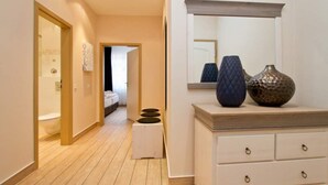 A hotel hallway with wooden flooring, a white dresser with drawers, and a mirror above it.