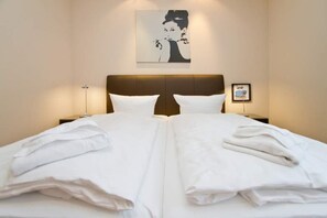 A neatly made bed with white linens and pillows, a brown headboard, a bedside table with a lamp, and a framed picture on the wall. - Seehof Bansin, App. 11 (Heringsdorf)