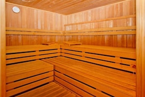 Eine Holzsauna mit Bänken und einer Bedienkonsole an der Wand.