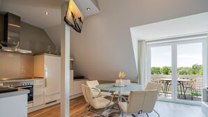 Een moderne keuken met een eethoek, grote ramen en uitzicht op de omgeving.