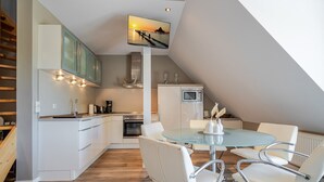 Een moderne keuken met een eethoek, een aan het plafond gemonteerde televisie en een trap.
