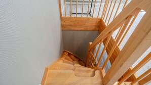 Een houten trap met een leuning en een plateau.