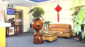 A modern lobby with a reception desk, a sofa, a coffee table, and decorative plants. - 7 Days Inn (Changzhou North Railway Station) (Changzhou)
