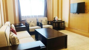 A hotel room with a sofa set, a coffee table, a TV mounted on the wall, and a window with curtains. - 7 Days Inn (Changzhou North Railway Station) (Changzhou)