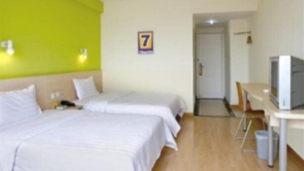A hotel room with two beds, a desk with a television, and a door leading to another room. - 7 Days Inn (Changzhou North Railway Station) (Changzhou)