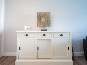 Um armário branco com três gavetas e um objeto decorativo em cima.