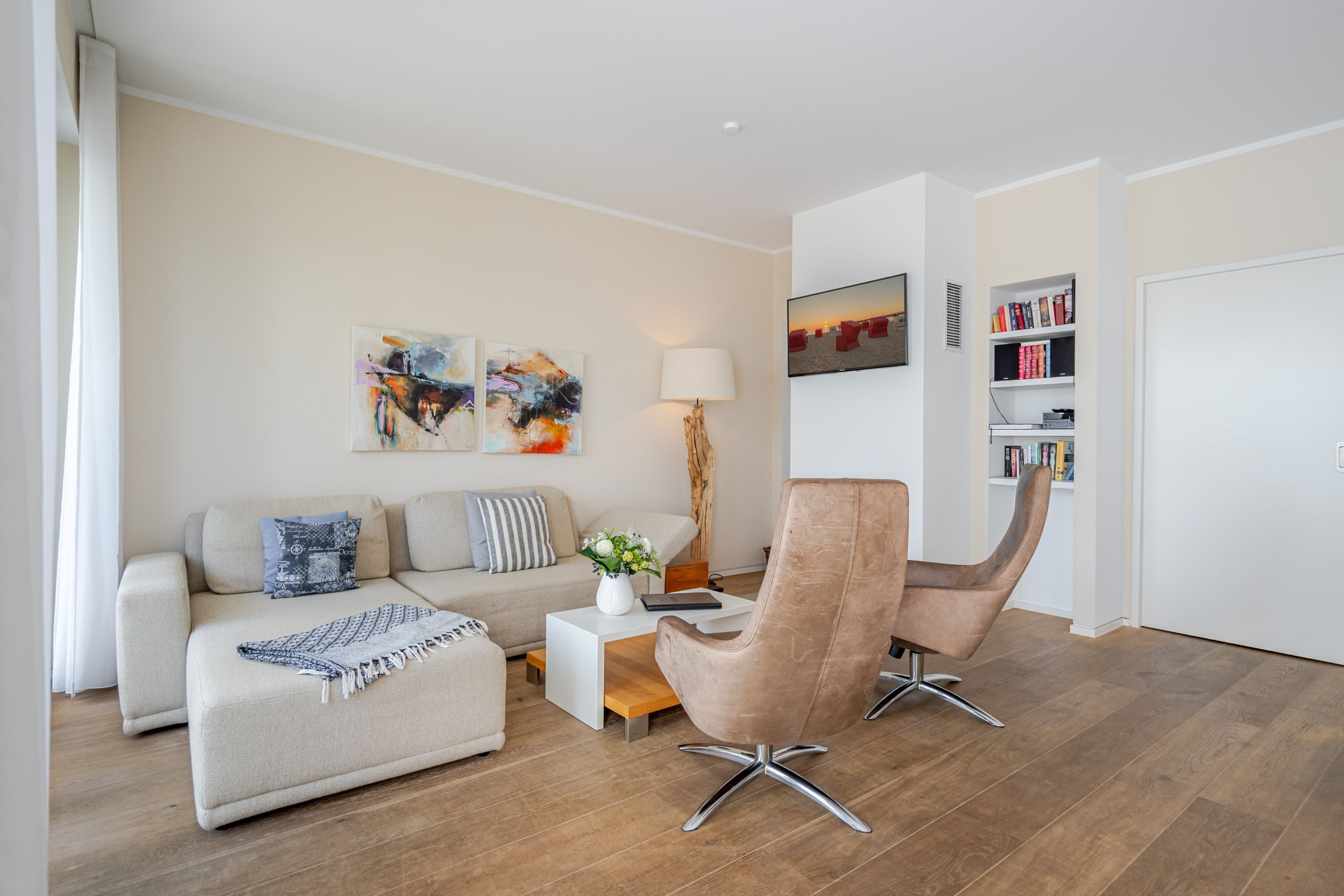 Un salon moderne comprenant un canapé, un fauteuil, une table basse et une bibliothèque.