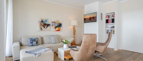 Uma sala de estar moderna com sofá, poltrona, mesa de centro e estante de livros.
