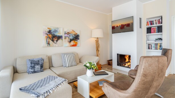 Un salon comprenant un canapé, un fauteuil, une table basse, une cheminée et des œuvres d’art accrochées au mur.