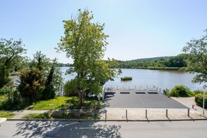 A lakeside dock with a paved walkway, trees, and a clear view of the water.