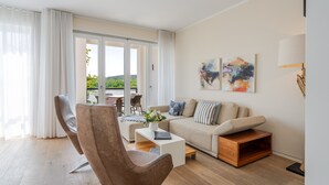 Un salon moderne avec un canapé, un fauteuil, une table basse et des œuvres d’art accrochées au mur.