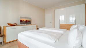 Une chambre d’hôtel moderne équipée d’un lit, d’une télévision, d’une table de chevet en bois et d’une armoire.