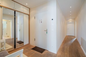 A hallway with a white door, a mirror, and a bench.