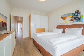 Une chambre d’hôtel avec un grand lit, une tête de lit en bois, une armoire et un tableau au mur.