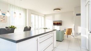 A modern kitchen with a large island, white cabinetry, and pendant lighting.