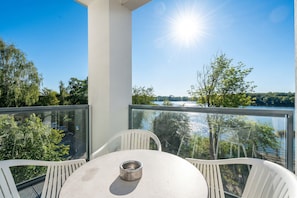 Ein Balkon mit Tisch und Stühlen mit Blick auf einen See und Bäume.