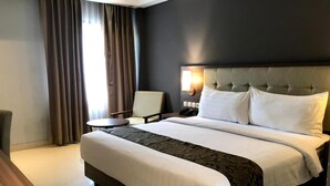 A hotel room with a large bed, a bedside table, a chair, and a desk. - Jatiluhur Hotel Valley & Resort (Purwakarta)