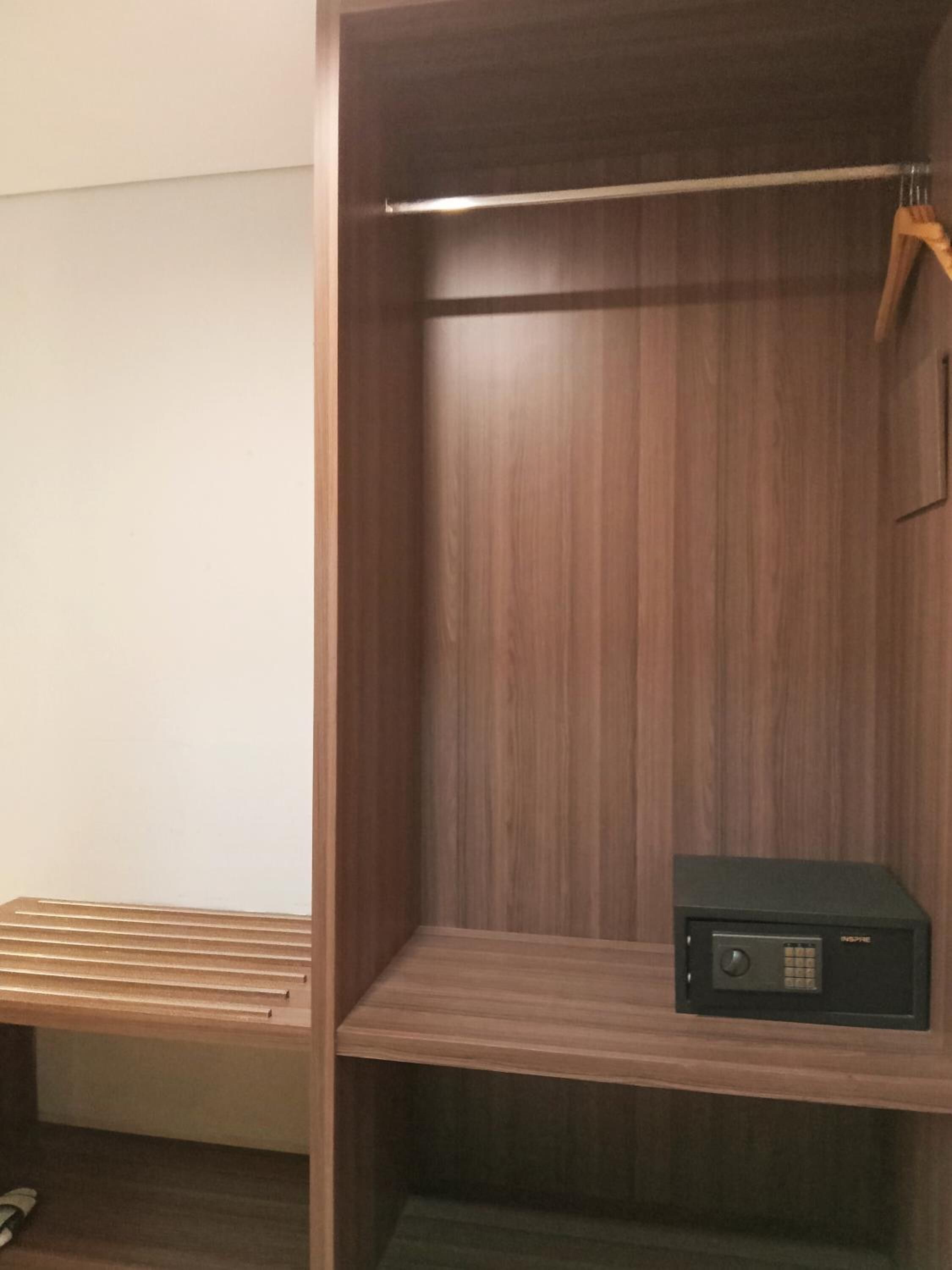 Un armario de madera con una barra para colgar y un estante.