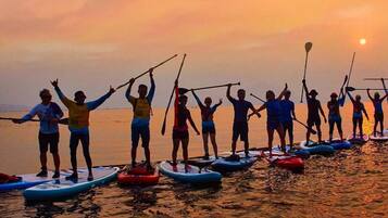 A group of people paddleboarding on a calm body of water during sunset.