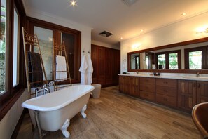 A spacious bathroom with a freestanding bathtub, wooden cabinets, and a large mirror.