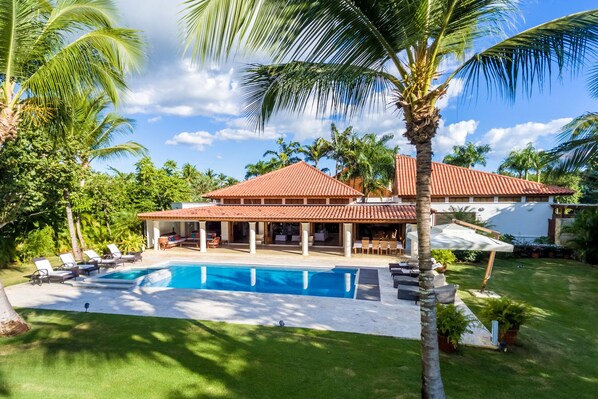 Ein Resort mit Swimmingpool, Liegestühlen und Palmen.