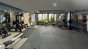 A spacious gym with various exercise equipment, large windows, and a view of greenery outside. - Marina Turquesa - Apartment 2 bedrooms 2 bathrooms and terrace garden views (Nerja)