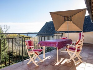 Ein Balkon mit Tisch und Stühlen, einem großen Sonnenschirm und Blick auf die Landschaft.