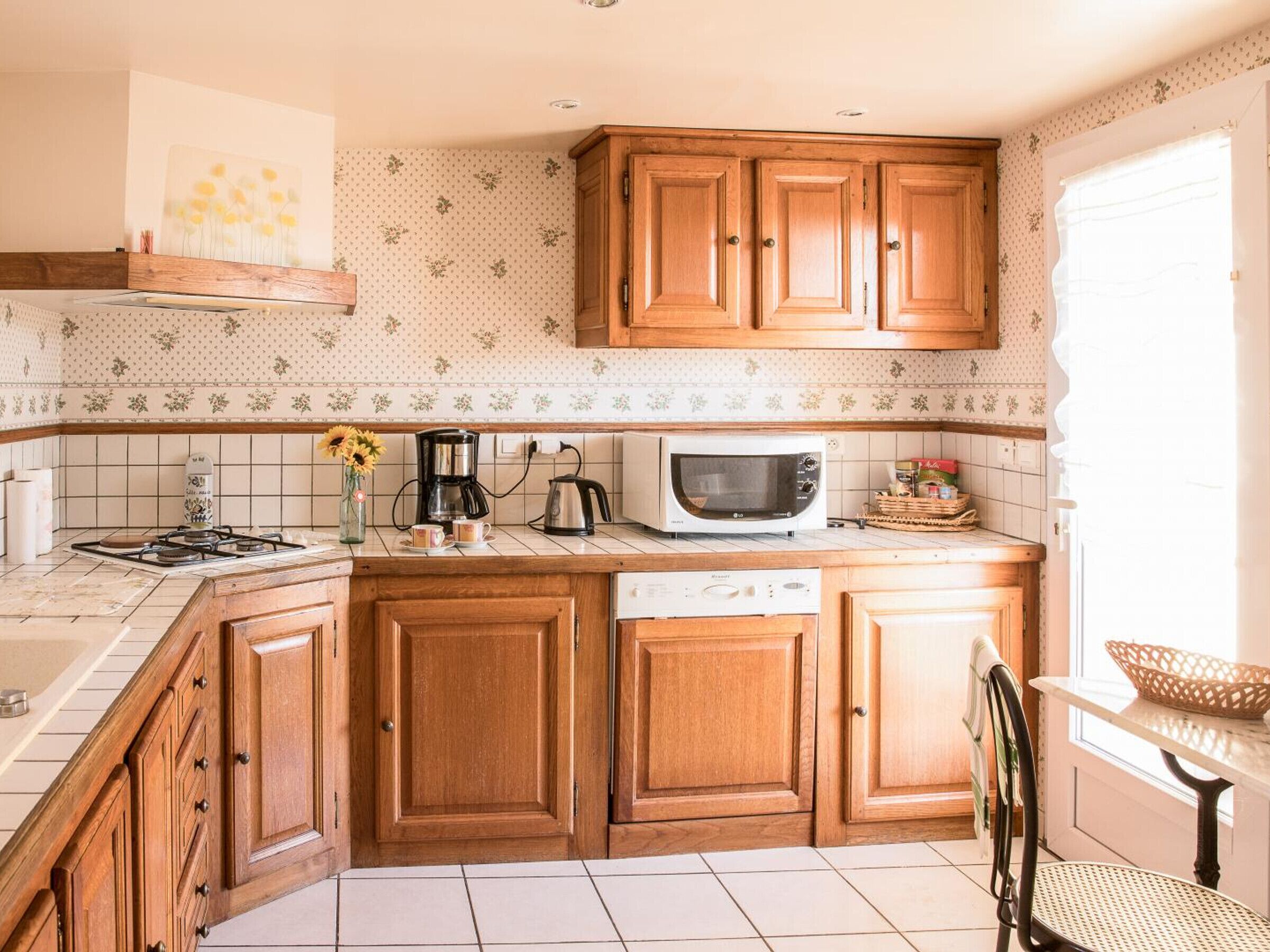 Una cocina con armarios de madera, microondas, cafetera y fregadero.