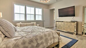 A bedroom with a large bed, a dresser, a TV, and a window. - Modern Lewes Home w/ Deck, Grill + Pond View! (Lewes)