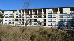 A multi-story residential building with balconies, a flat roof, and a clear blue sky. - Cosy 2-Room Apartment with Parking, Private Ski Locker, and Modern Amenities in Bolquère (Bolquère-Superbolquère)