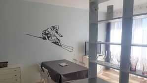 A dining area with a table, chairs, and a wall decal of a skier. - Cosy 2-Room Apartment with Parking, Private Ski Locker, and Modern Amenities in Bolquère (Bolquère-Superbolquère)