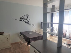 Uma sala de jantar com uma mesa, cadeiras e um adesivo na parede com o desenho de um esquiador.