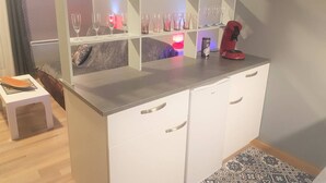 A compact kitchen with white cabinets, a coffee machine, and a shelf with glassware. - Cosy 2-Room Apartment with Parking, Private Ski Locker, and Modern Amenities in Bolquère (Bolquère-Superbolquère)