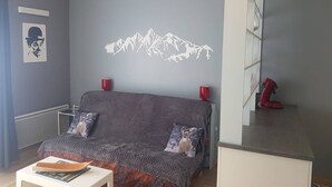 A modern bedroom with a bed, a small table, and a red chair. - Cosy 2-Room Apartment with Parking, Private Ski Locker, and Modern Amenities in Bolquère (Bolquère-Superbolquère)